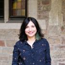 Camli Badrya stands with hands in pockets against a brick background